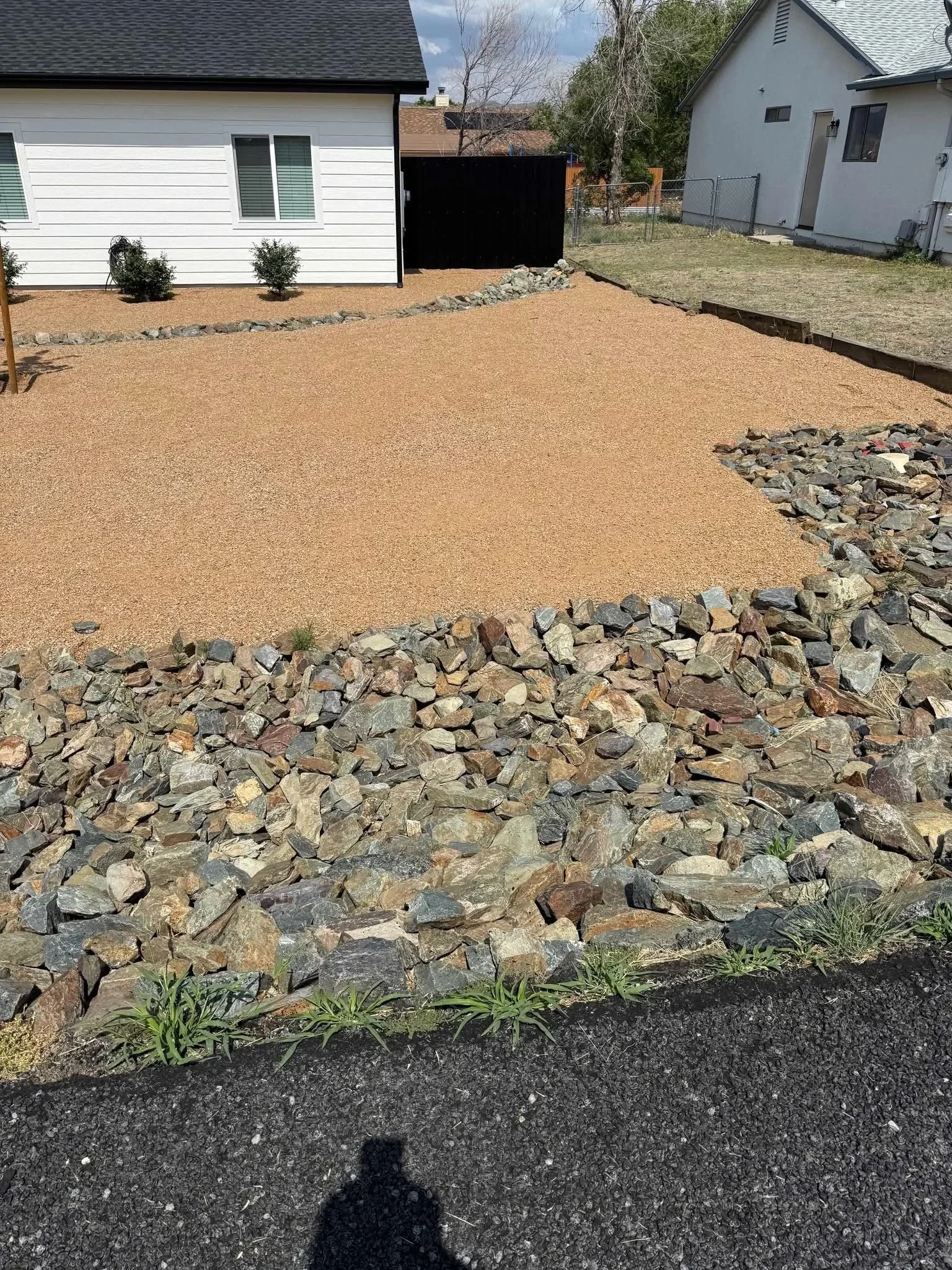 Tan gravel patio with natural stone rock edging in residential backyard