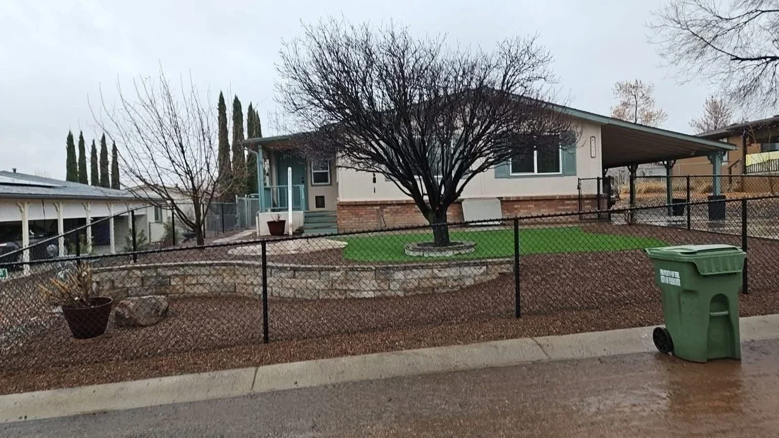 Black chain-link fenced residential yard with gravel, mature trees, and new sod in Prescott Valley