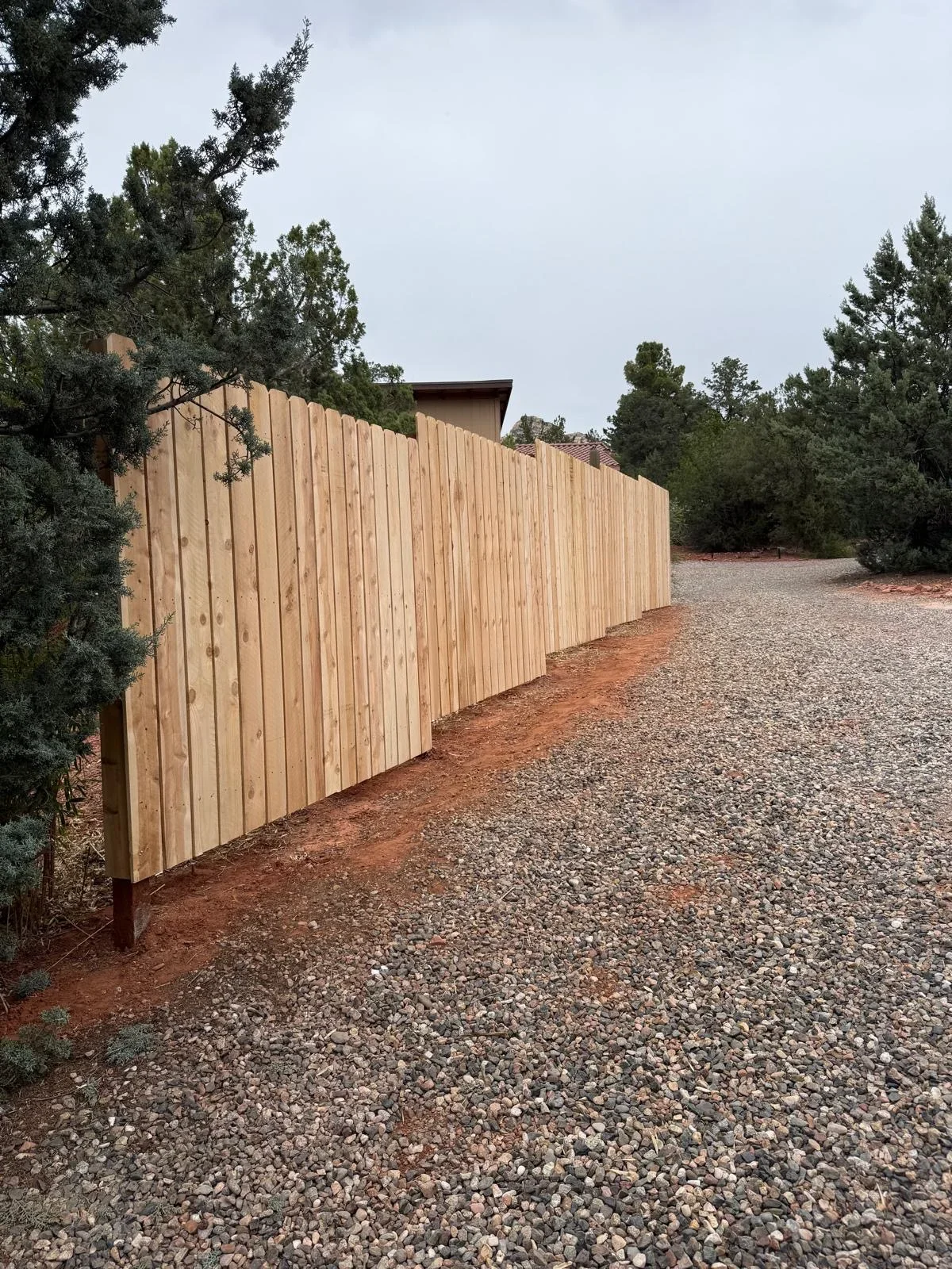 New cedar privacy fence with vertical boards along gravel driveway in Prescott Valley