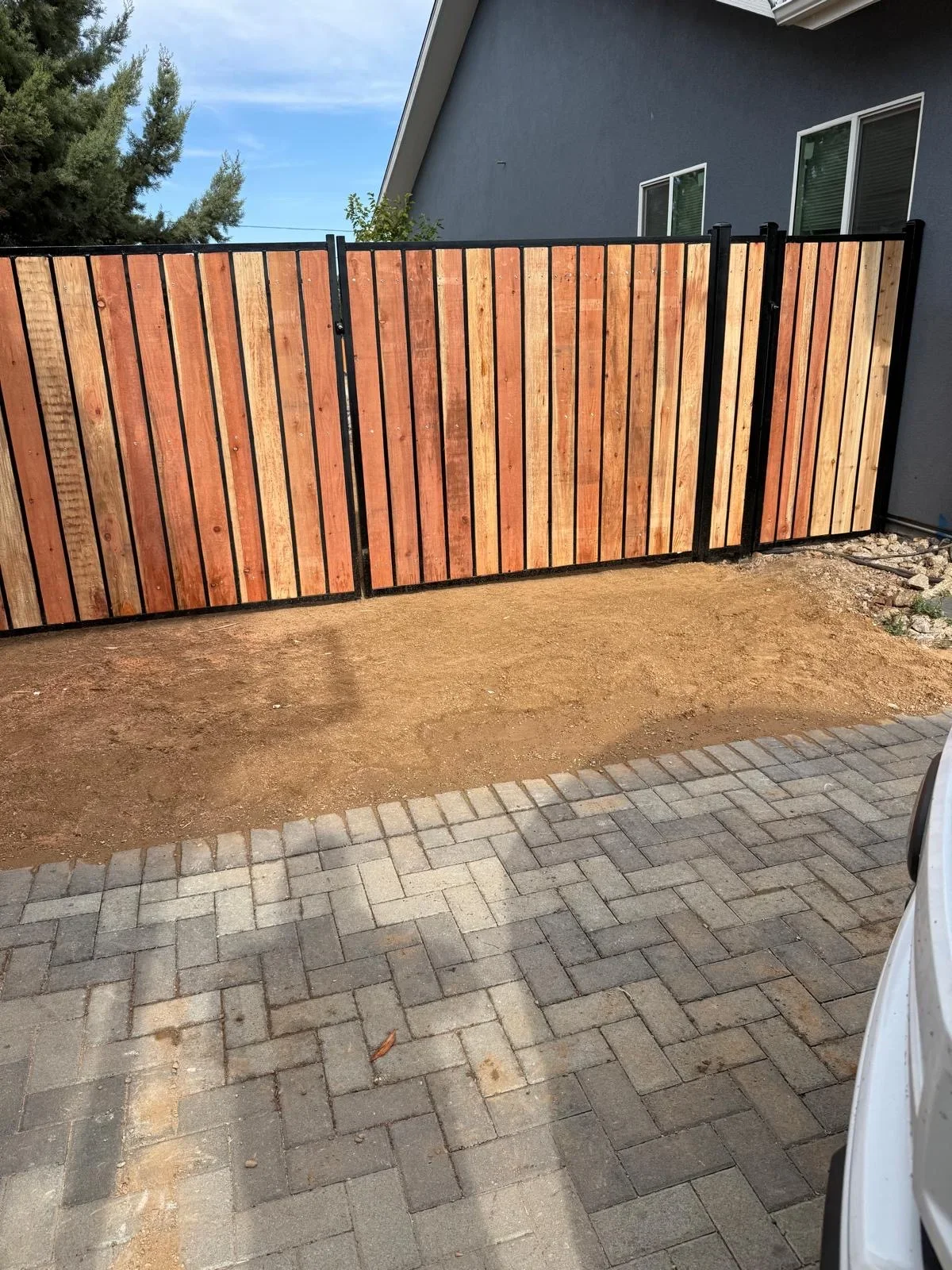 Modern wood and metal fence with vertical cedar slats and black frame in residential backyard