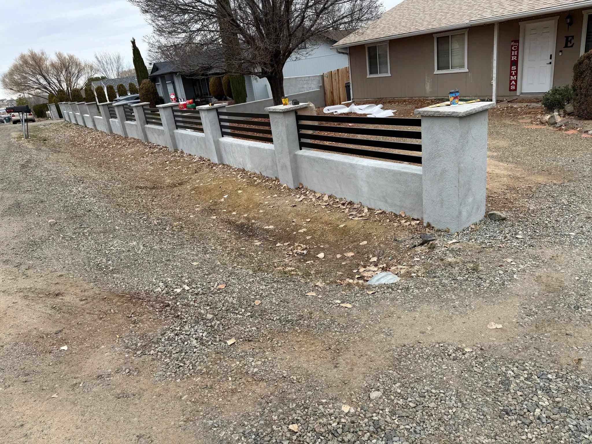 Modern concrete pillar fence with black metal horizontal slats along residential driveway