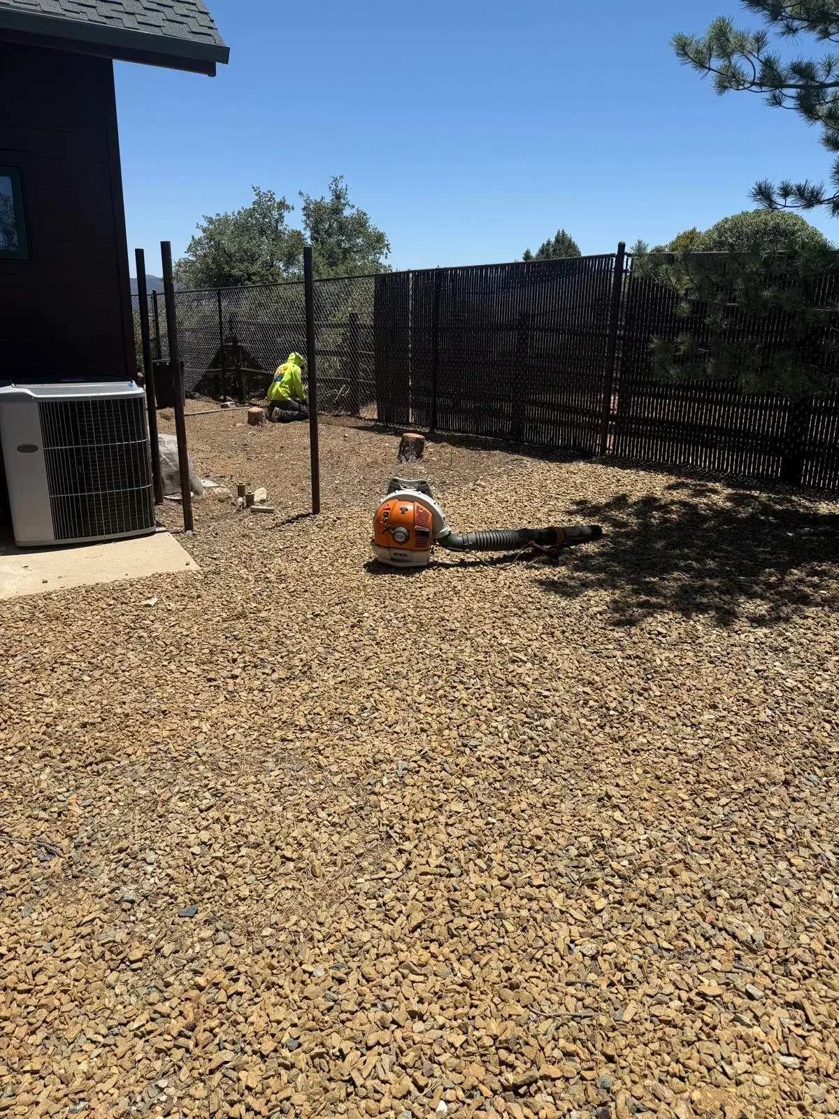 Black vertical slat fence installation with steel posts and gravel base in Prescott Valley